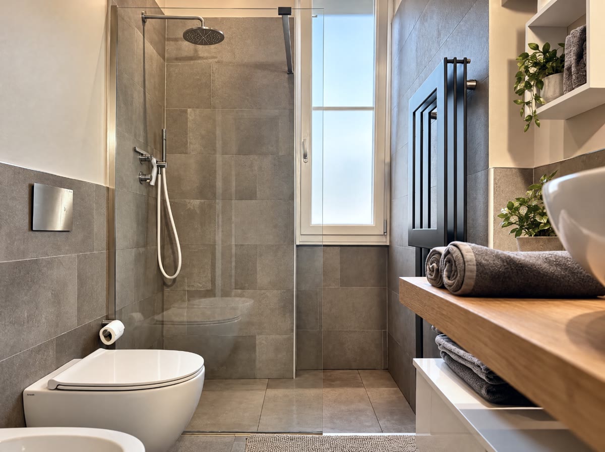 Bagno con doccia a filo, piano in legno e asciugamani arrotolati